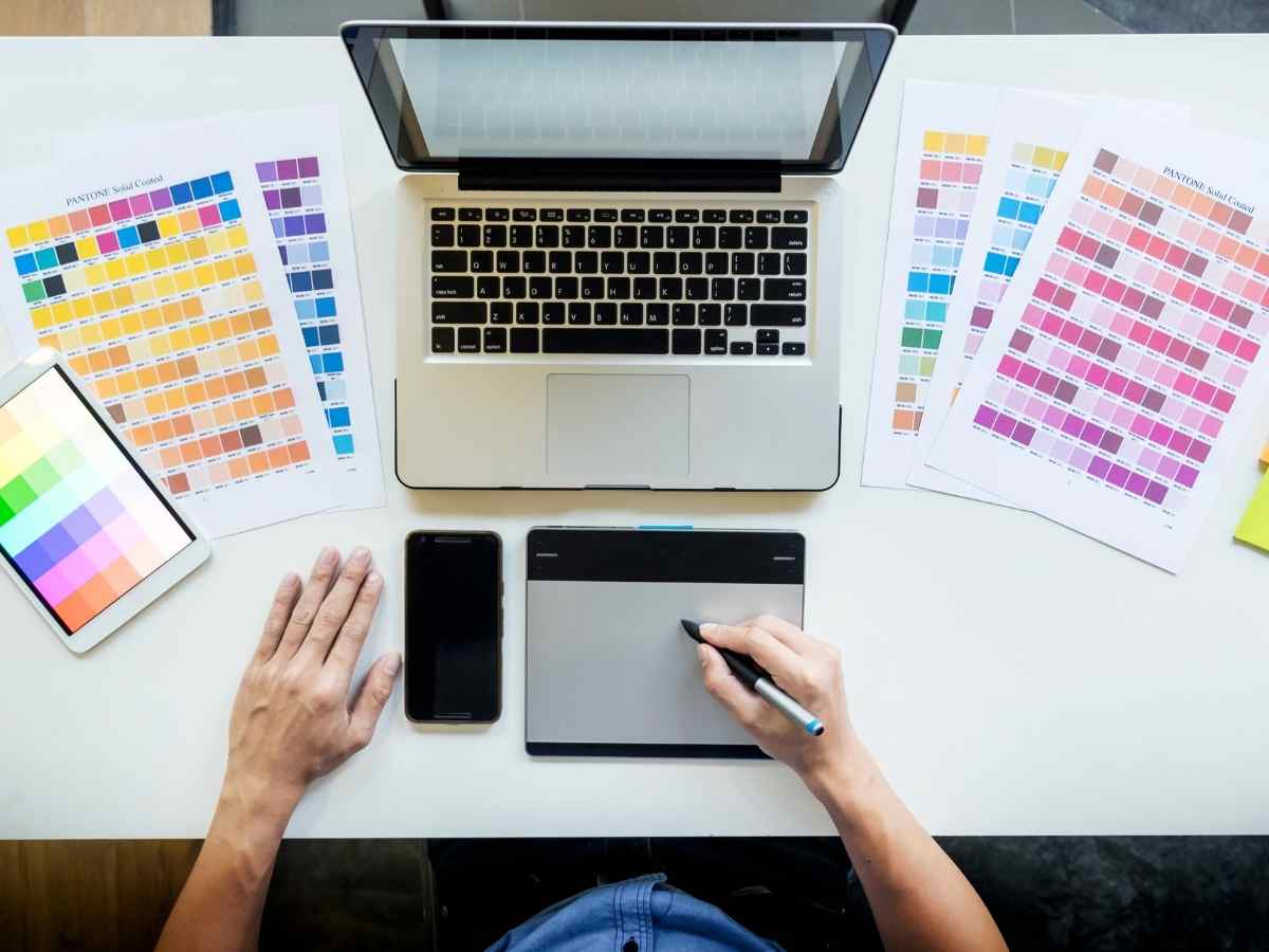 Visão geral de uma mesa de trabalho com computador e ferramentas de design, ideal para um projeto de mestrado em design gráfico.