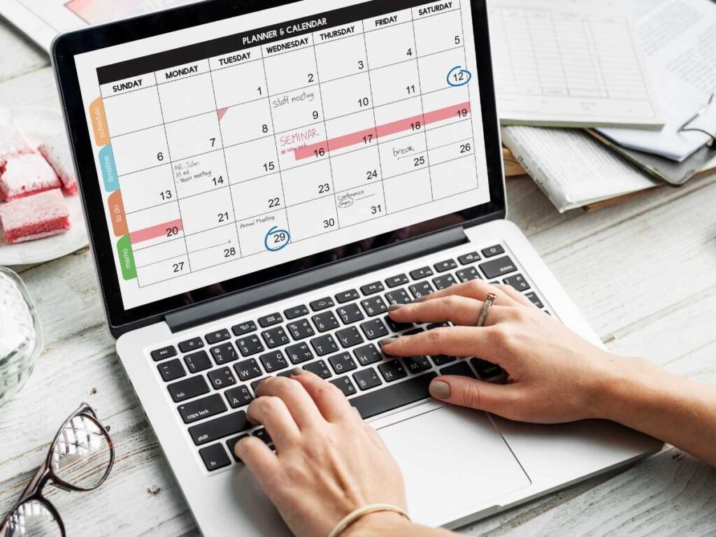 Pessoa digitando em laptop com calendário aberto na tela, representando o planejamento do cronograma de tese.