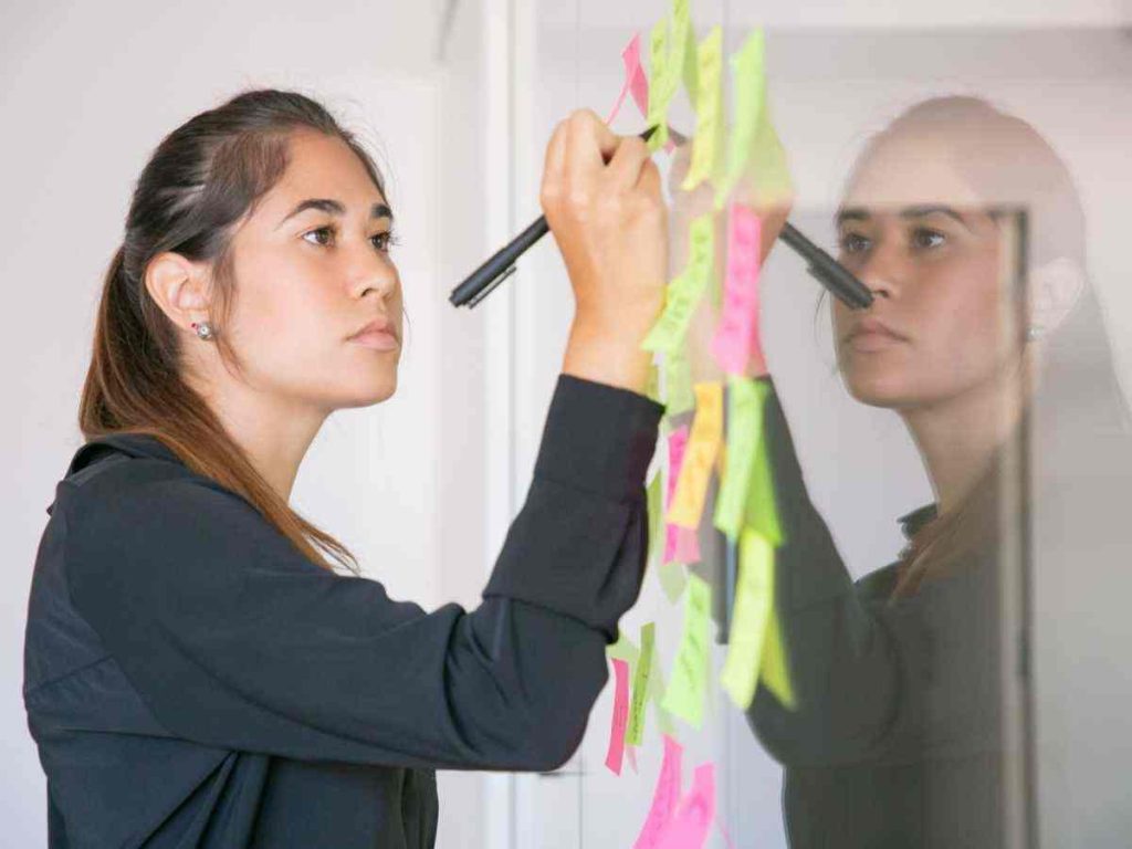 Imagem de pessoa preparando apresentação com post-its, refletindo a preparação para a defesa de tese