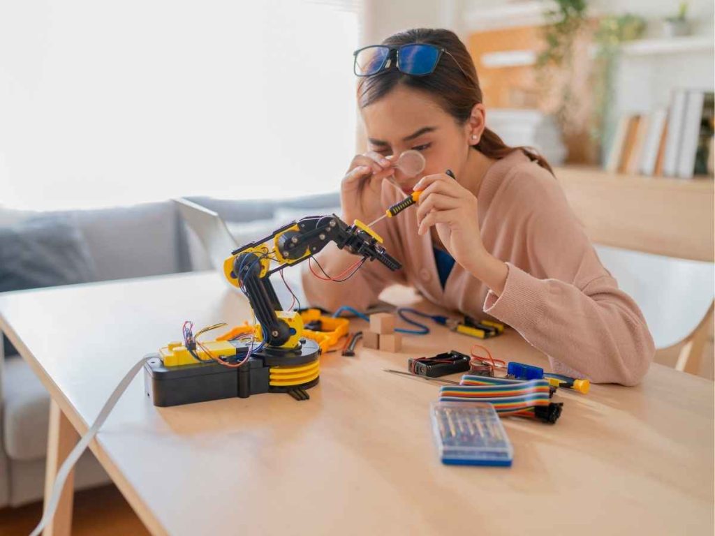 Pessoa montando robô com outra usando óculos VR, em ambiente de laboratório