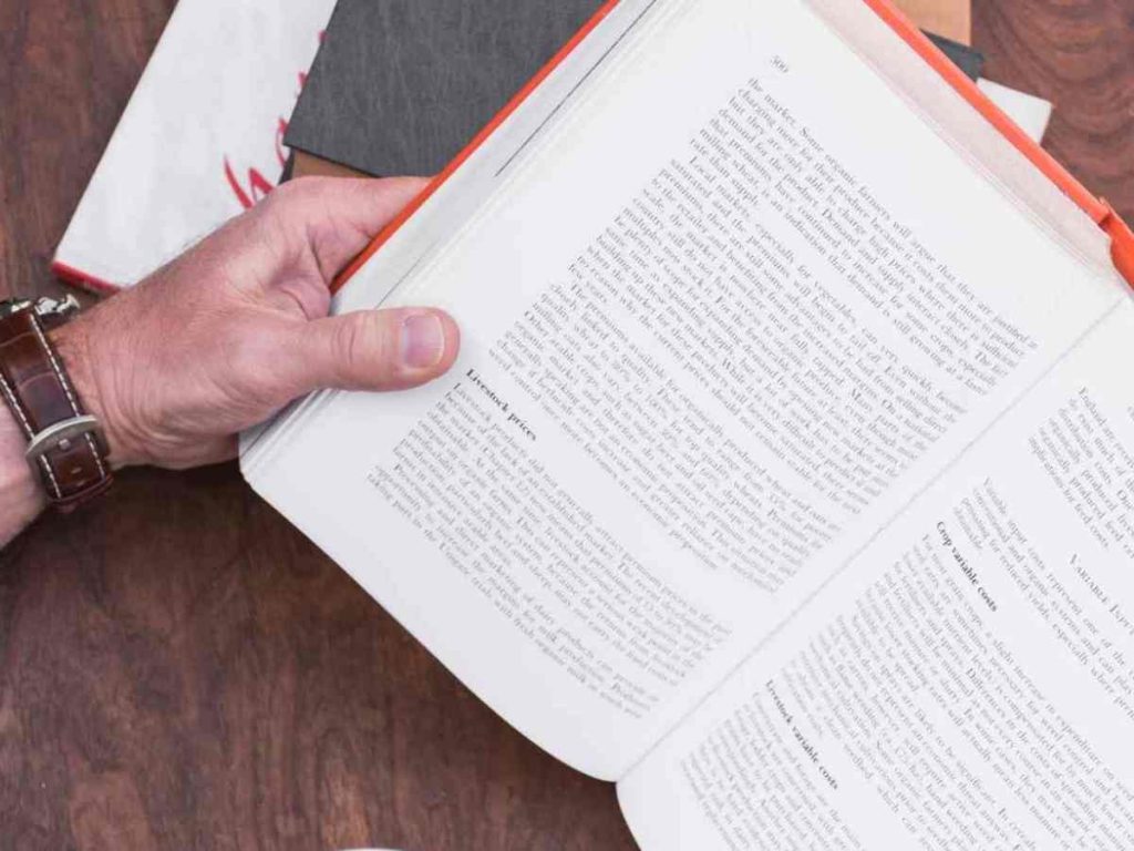 Imagem de mãos passando páginas de livro, simbolizando o processo de redação de um projeto de mestrado