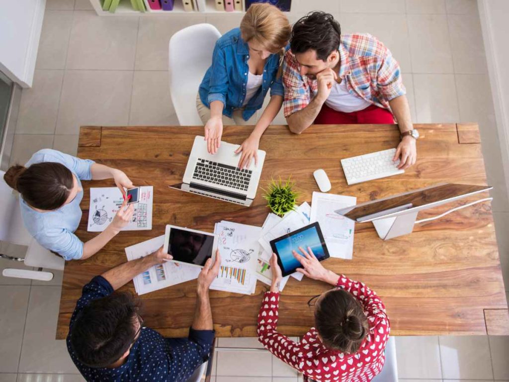 Grupo de pessoas discutindo e analisando gráficos e dados em uma mesa de trabalho
